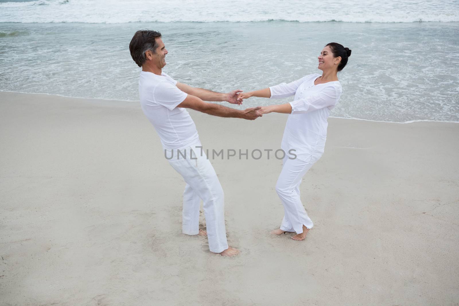 Romantic couple holding hands on beach by Wavebreakmedia