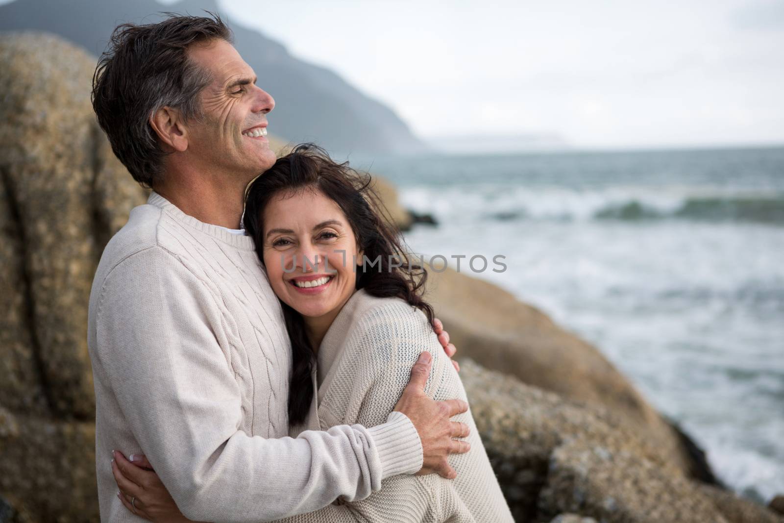 Romantic couple embracing each other on beach during winter