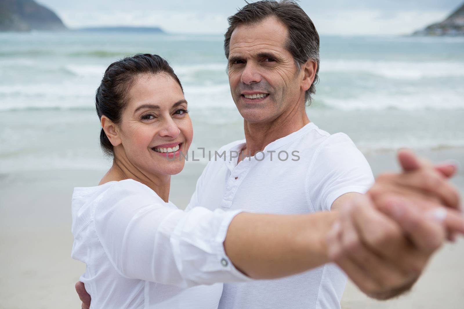 Portrait of romantic couple dancing on beach during winter