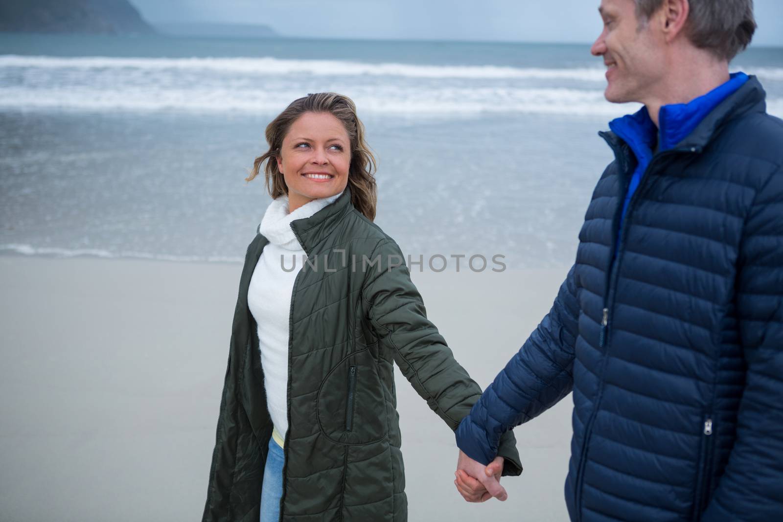 Romantic couple holding hands on beach during winter