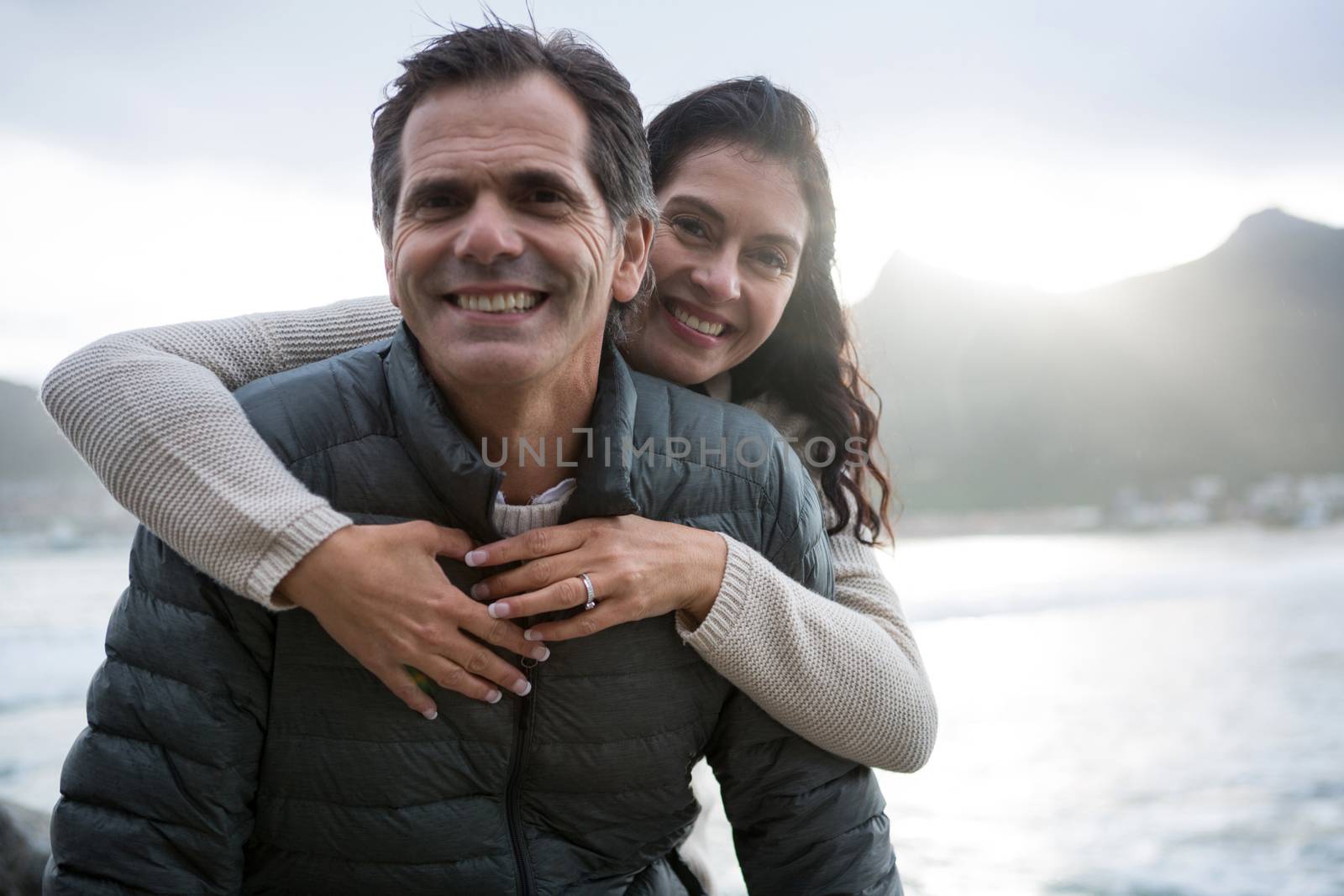 Portrait of romantic couple embracing each other on beach during winter