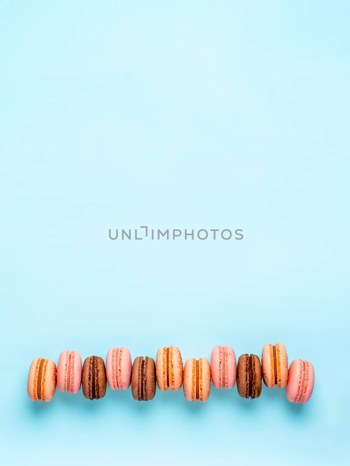 Macarons with copy space. Row of perfect french macarons or macaroons on blue background. Top view or flat lay