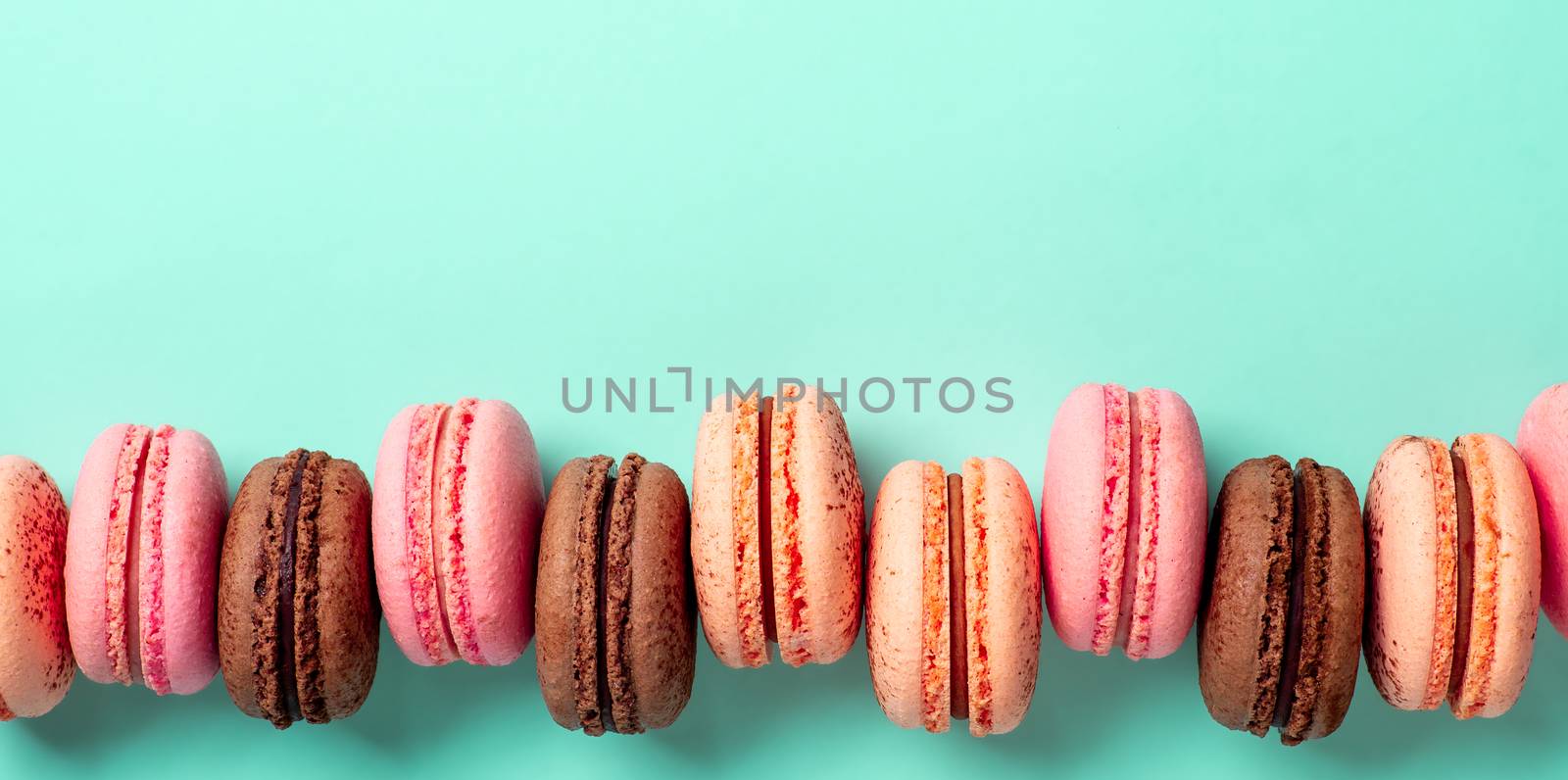 Macarons banner with copy space. Colorful french macarons or macaroons on blue turquoise background. Top view or flat lay