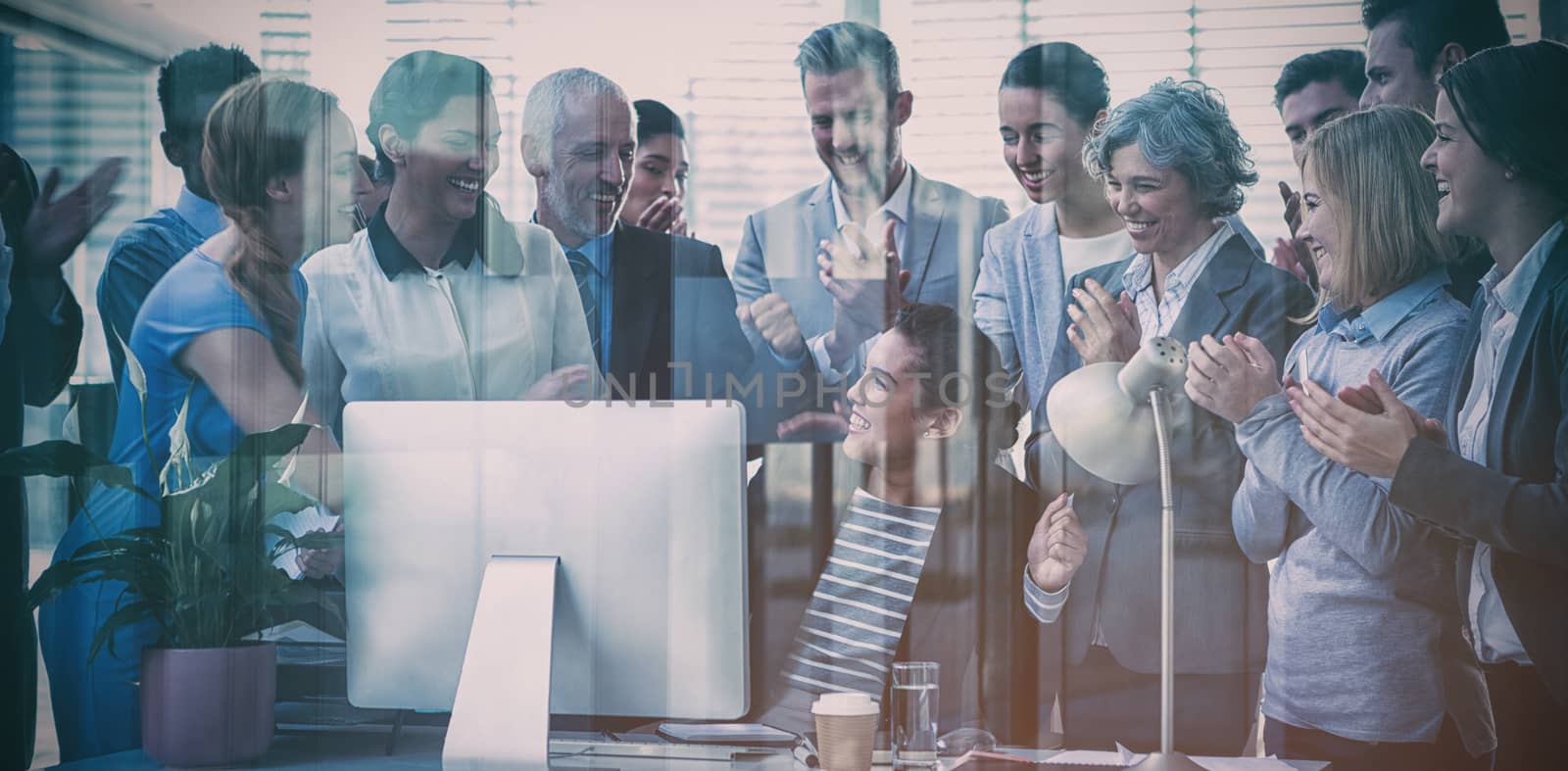 Business people applauding their colleague presentation in office seen through glass