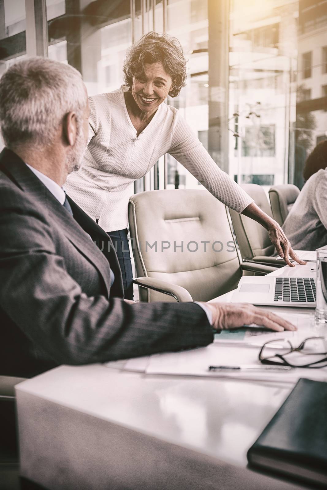 Smiling businesswoman standing by colleague in office