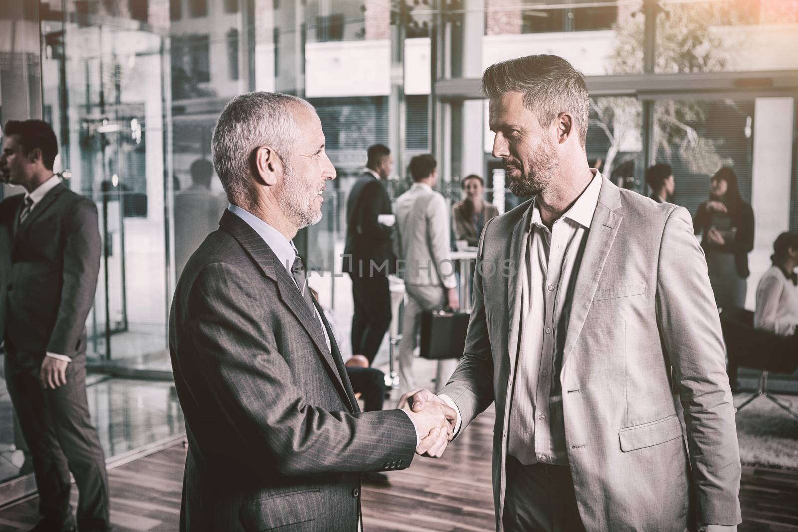 Confident businessmen shaking hands in office