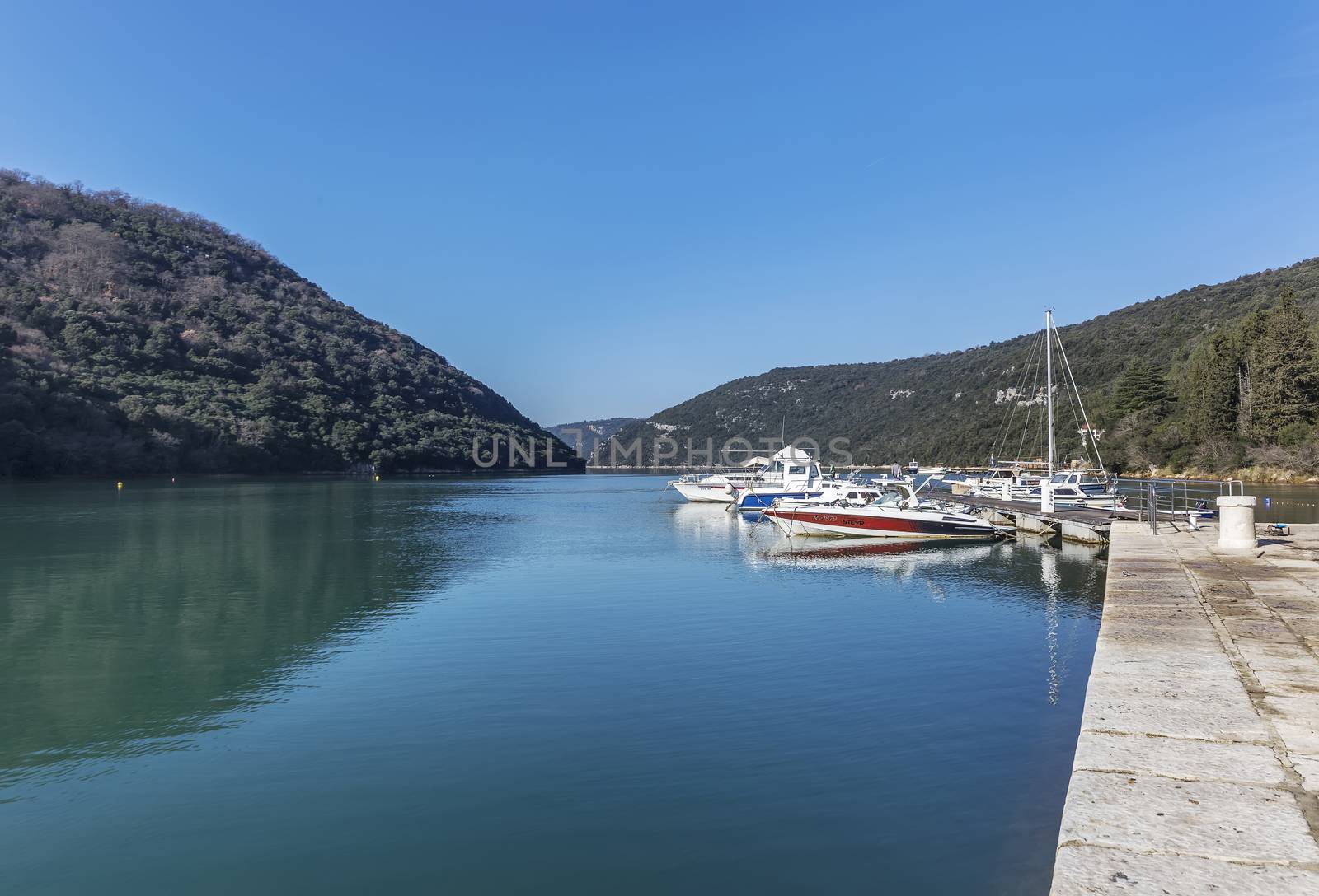 LIMSKI KANAL, CROATIA - January 29, 2020: Anchored boats in a sunny port in the Lim Canal, Istria, Croatia