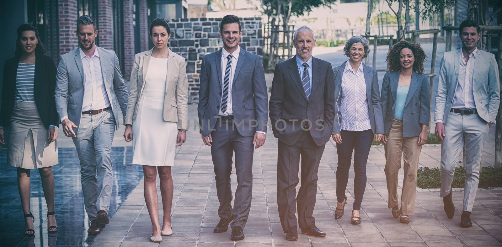 Portrait of smiling business people walking outside office building