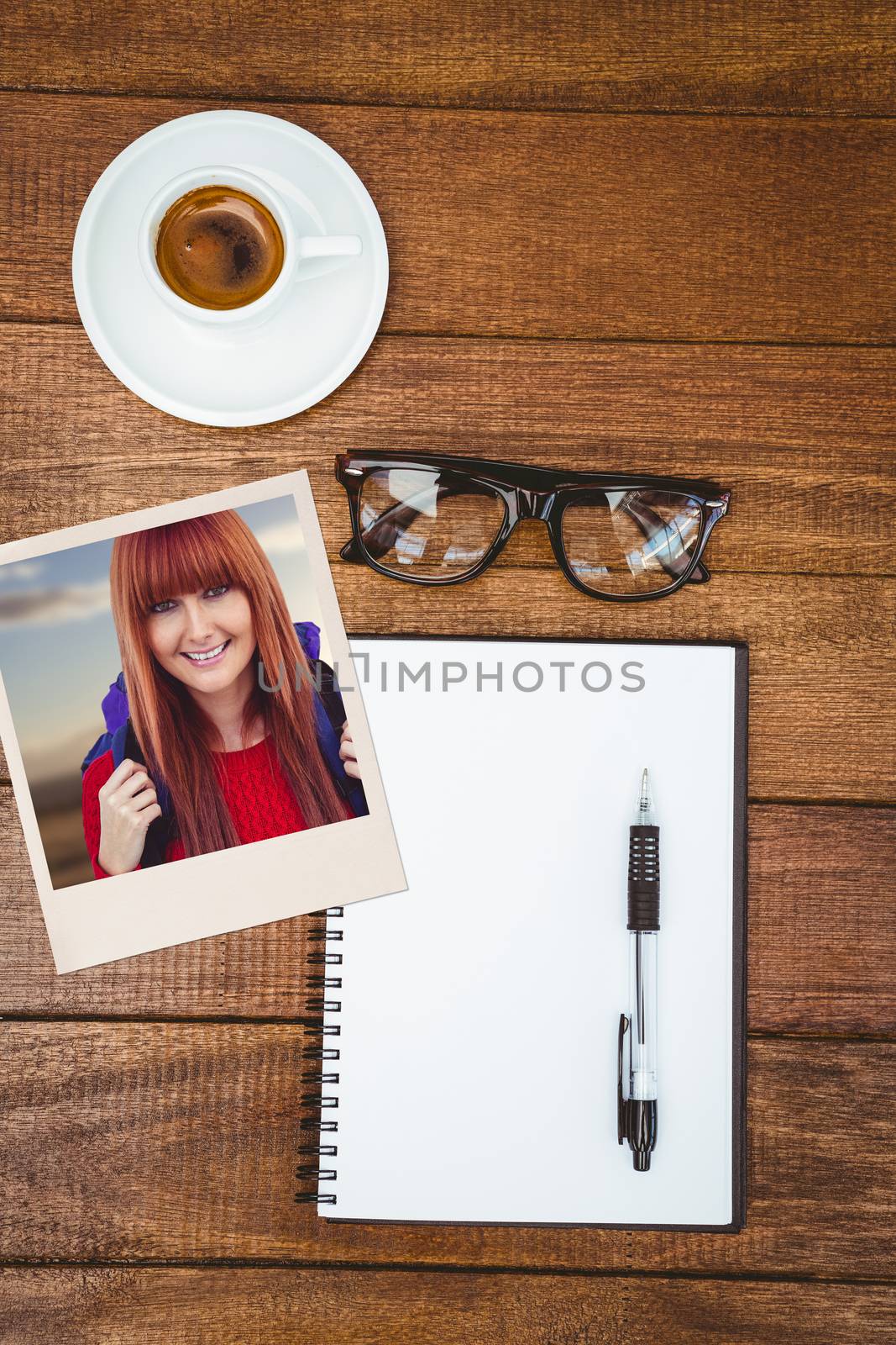 Smiling hipster woman with a travel bag taking selfie against above view of business desk
