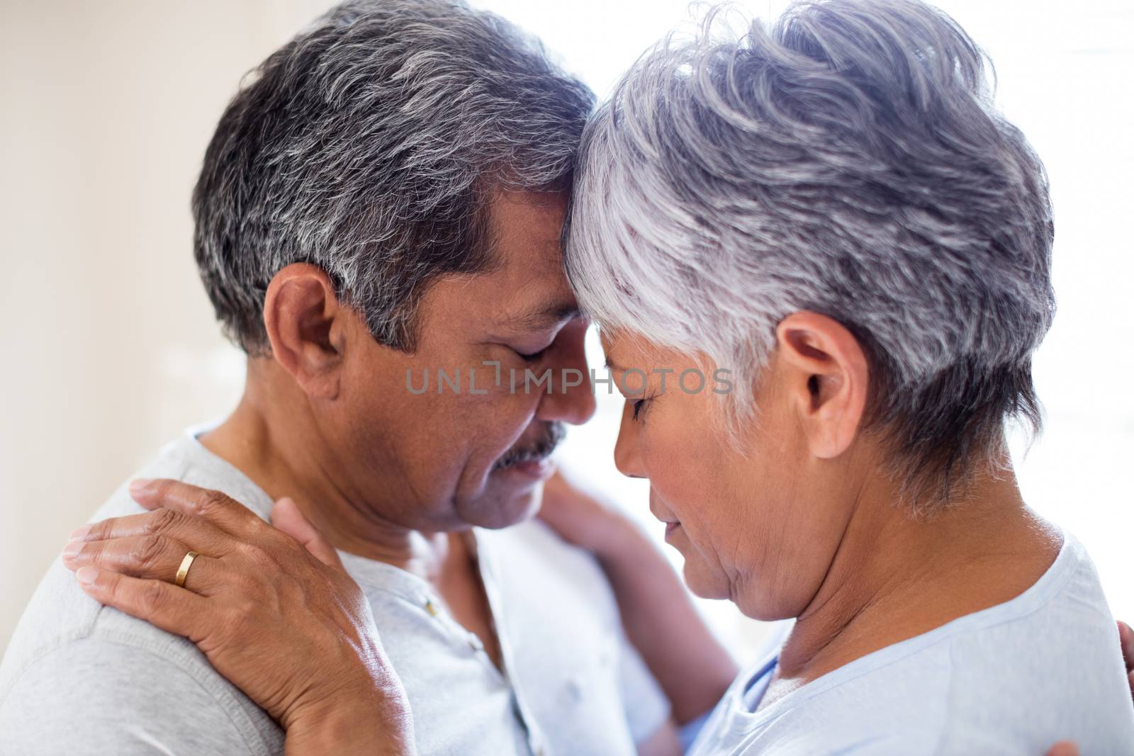 Romantic couple embracing face to face in bedroom at home
