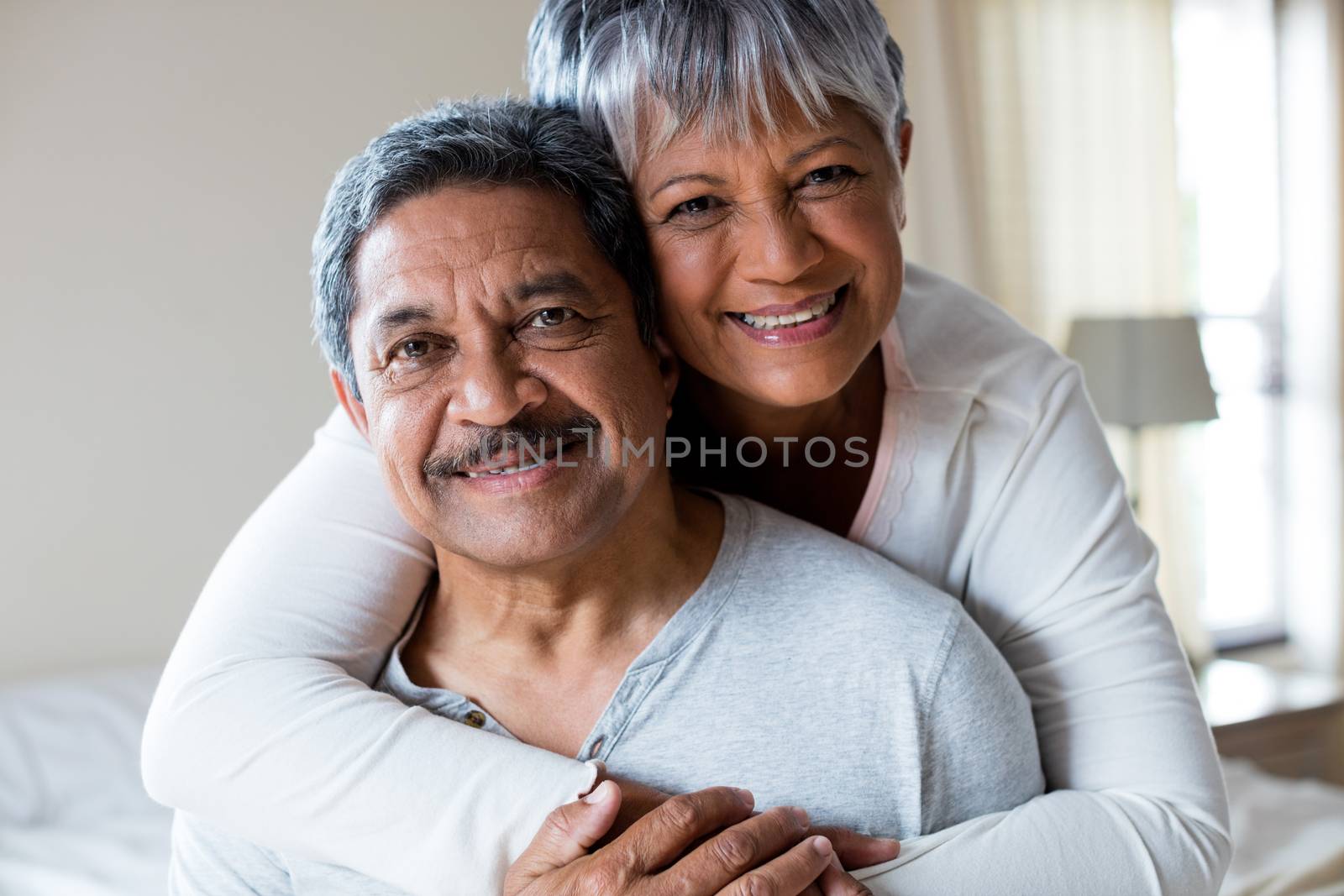 Portrait of romantic couple embracing in bedroom at home