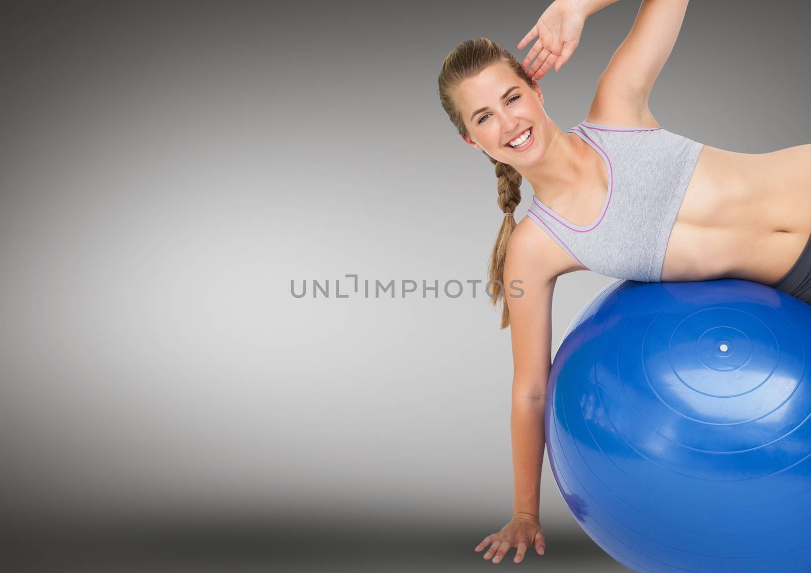 Portrait of woman performing exercise with fitness ball against grey background