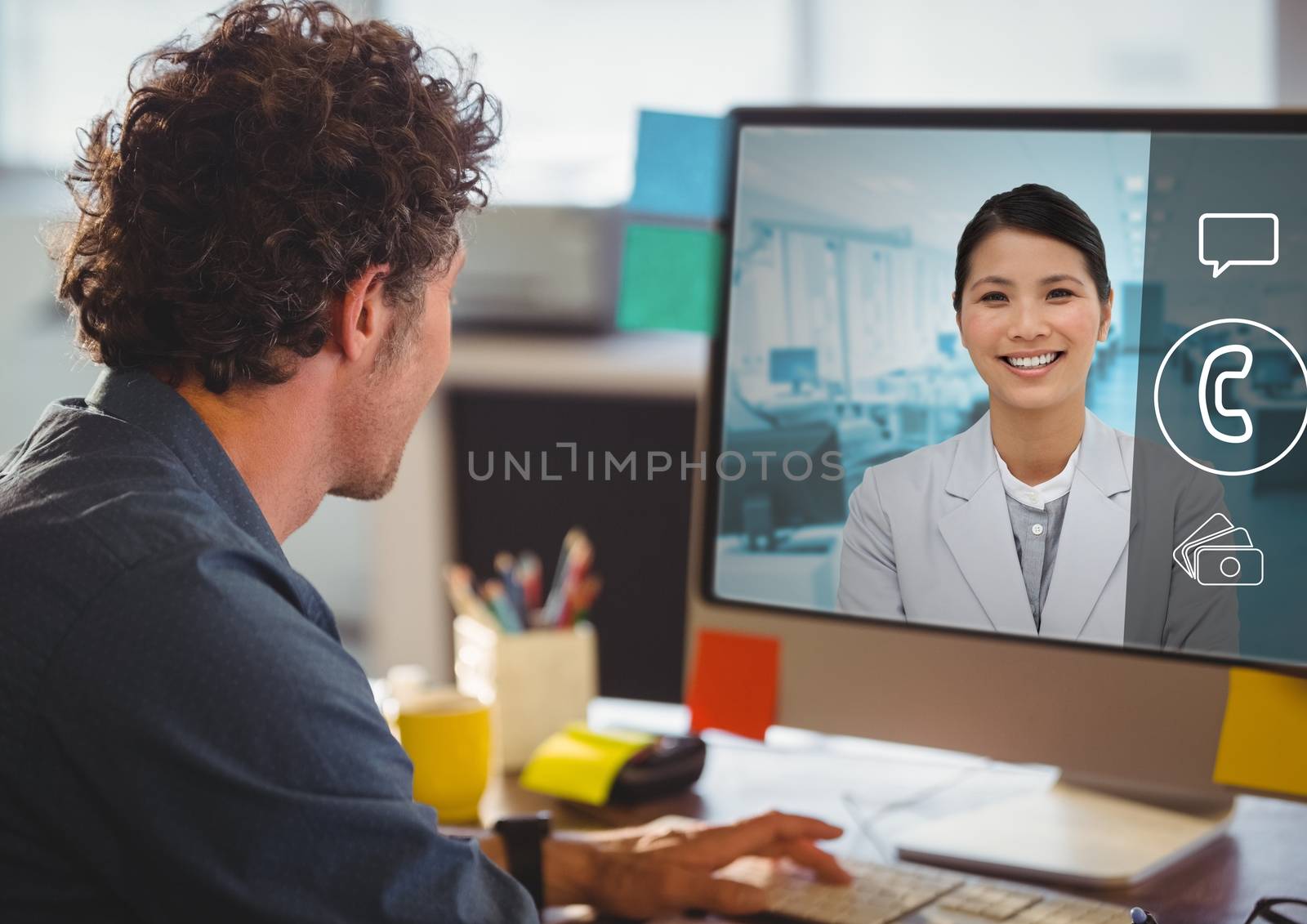 Rear view of man having a video call with his colleagues on desktop pc