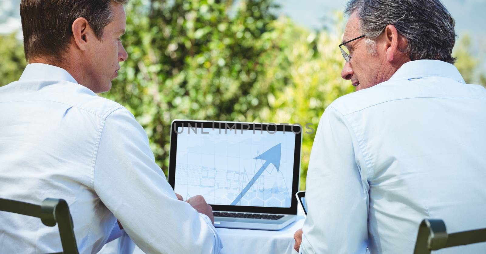 Business people discussing over laptop while sitting outdoors