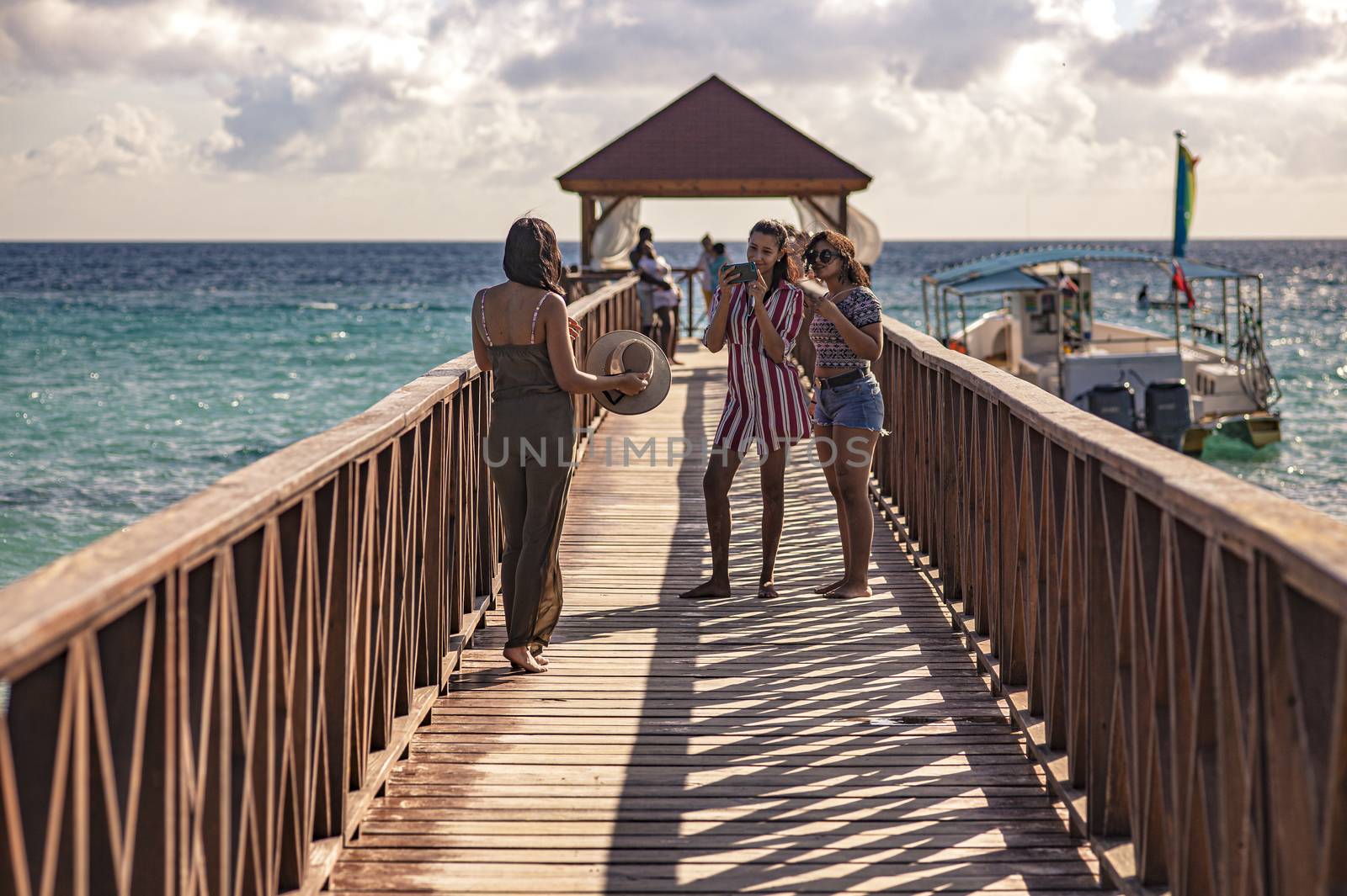 Girls take a picture with their smartphone on the Dominicus pier at sunset by pippocarlot