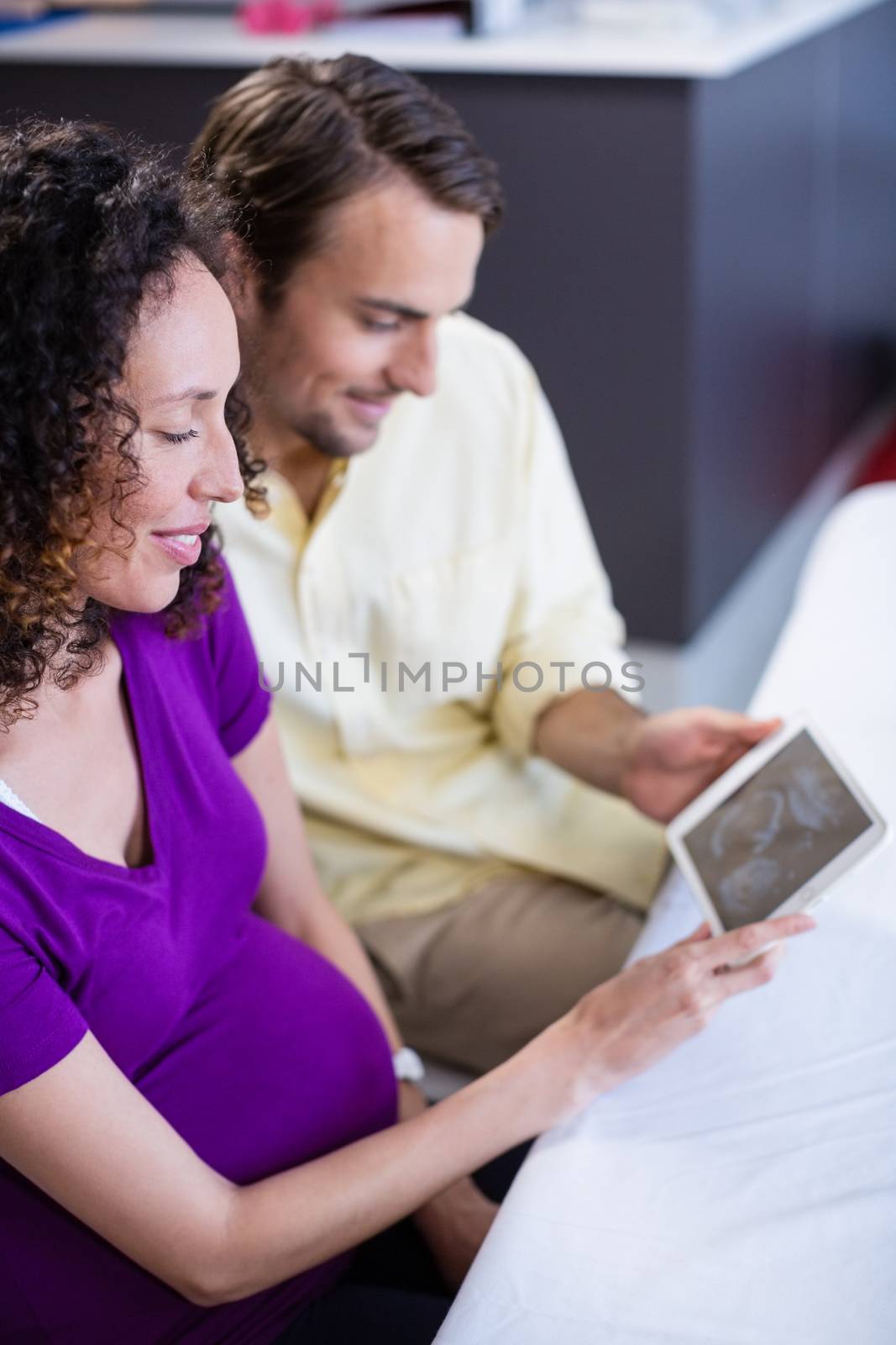 Couple looking at babies ultrasound scan on digital tablet in hospital
