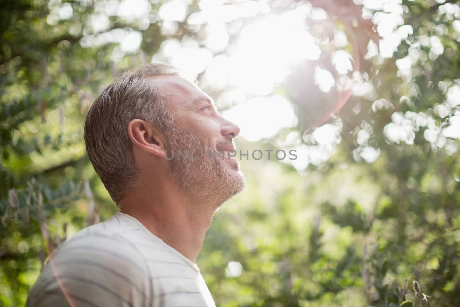 Smiling man standing against bright sunlight at park