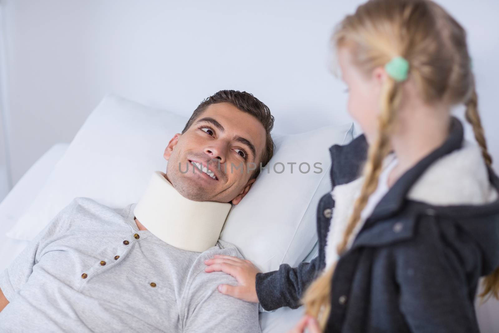 Smiling daughter comforting her sick father in hospital room