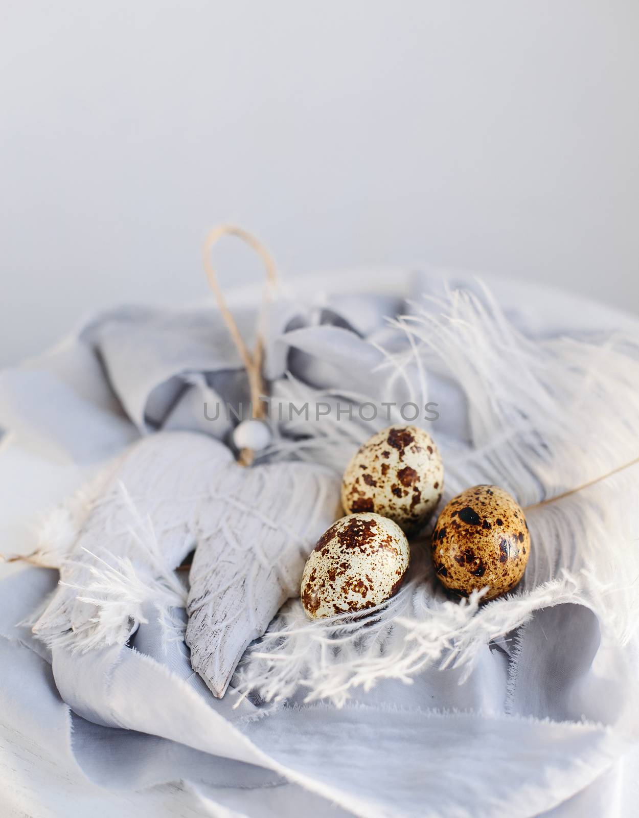 Easter eggs with white feather on white and gray background. Happy Easter holiday, front and top view.