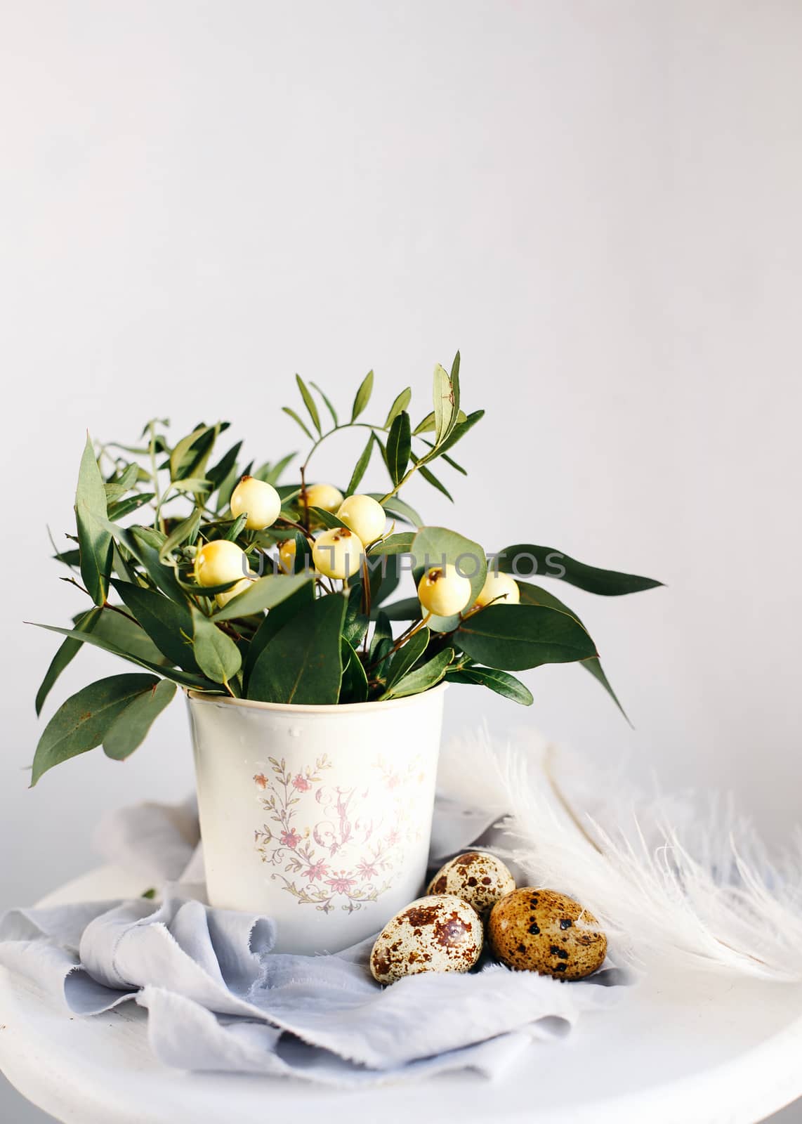 Easter eggs with green branches and yellow berries on white and gray background. Happy Easter holiday, front view.