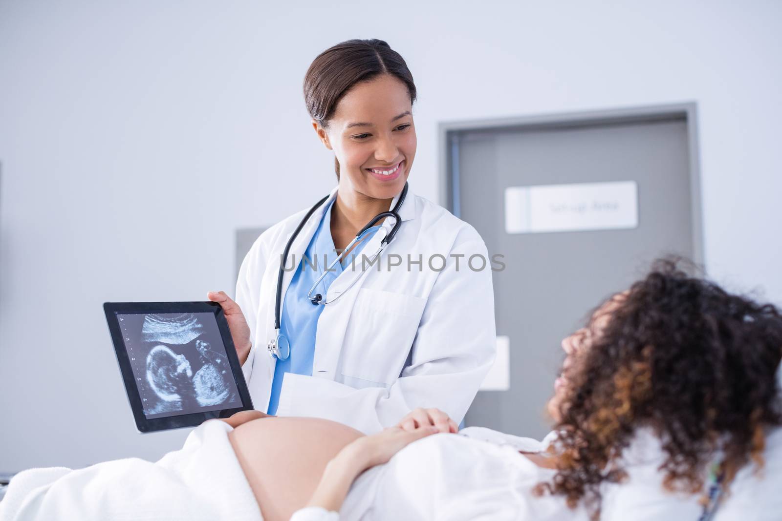 Doctor showing babies ultrasound scan to pregnant woman on digital tablet by Wavebreakmedia
