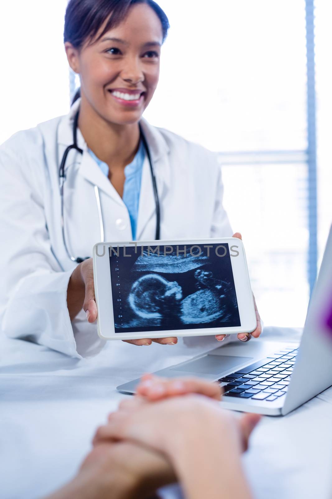 Doctor showing babies ultrasound scan on digital tablet in hospital