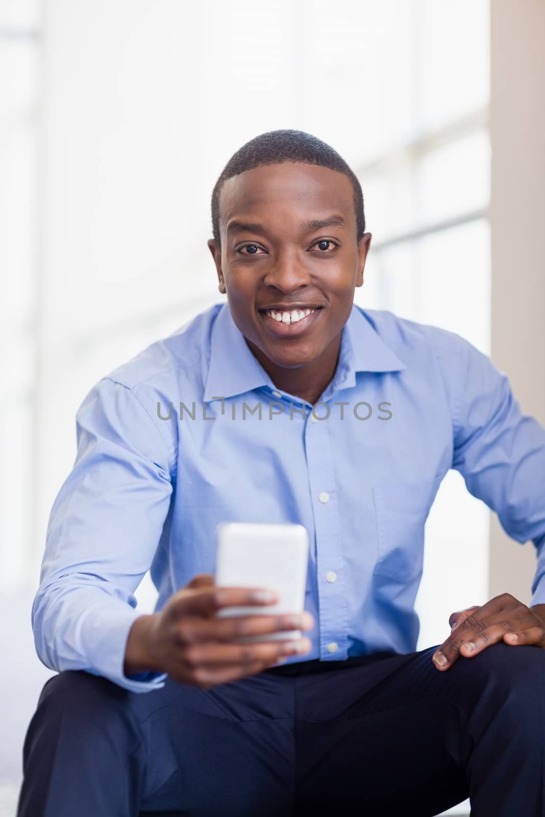 Portrait of a happy businessman holding mobile phone at conference centre