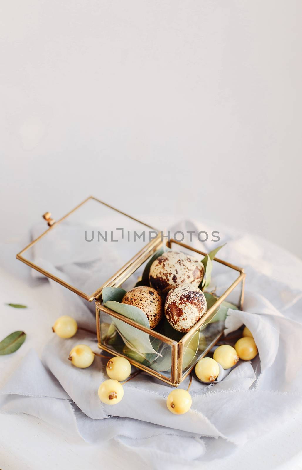 Easter composition. Easter eggs in a glass box on silk ribbons and on white and gray background.