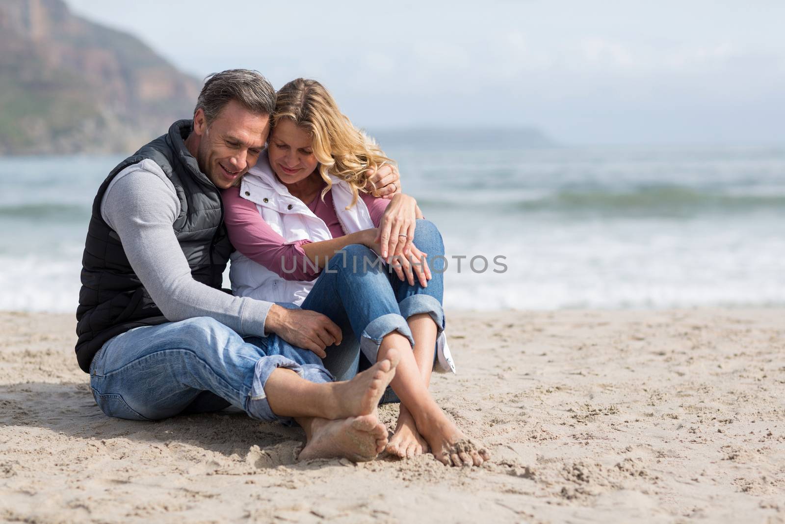 Romantic mature couple sitting together on the beach