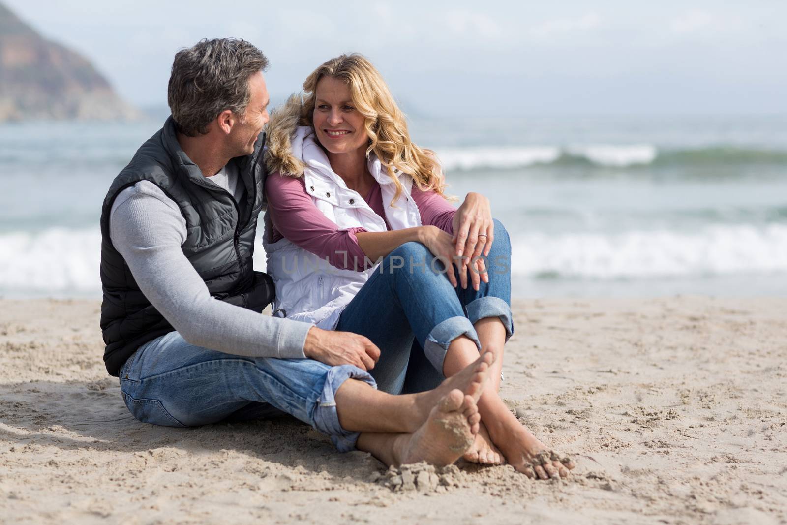 Romantic mature couple sitting together on the beach