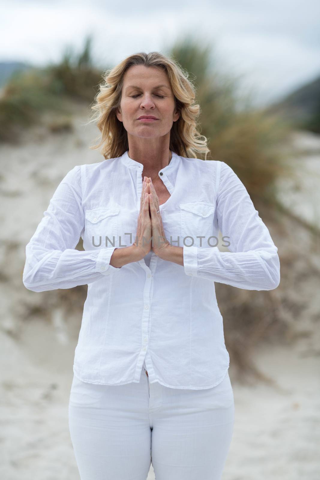 Mature woman doing meditation on the beach