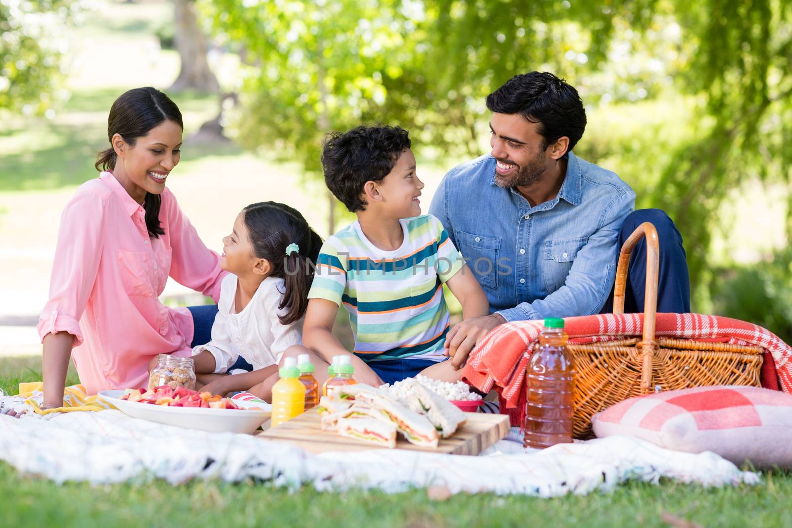 Happy family having breakfast in park on a sunny day