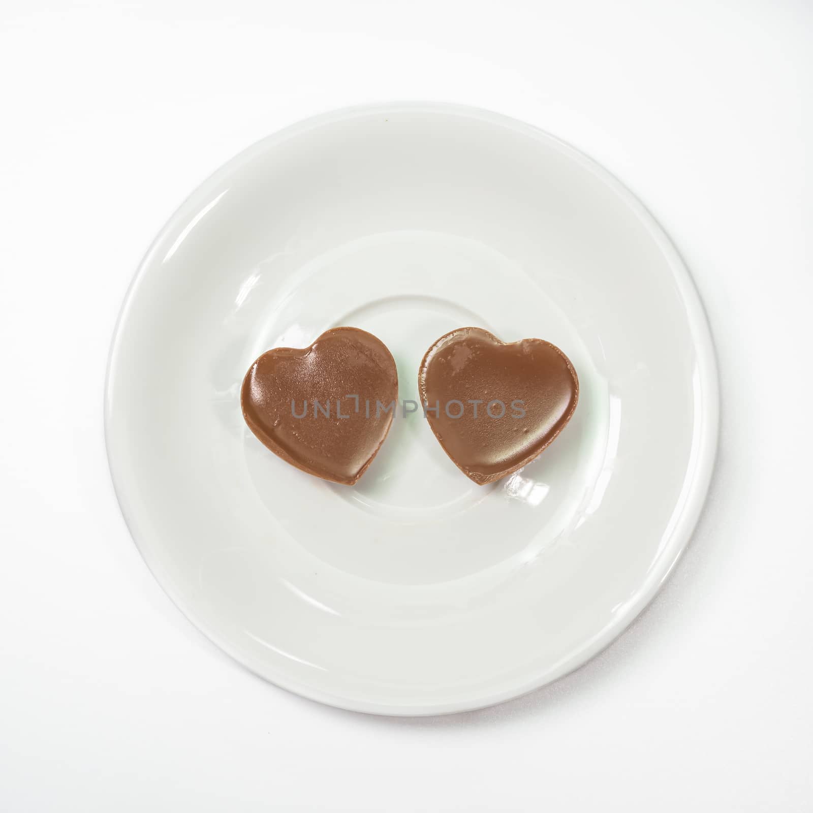 The close up of Love heart shape chocolate on coffee cup plate on white background.