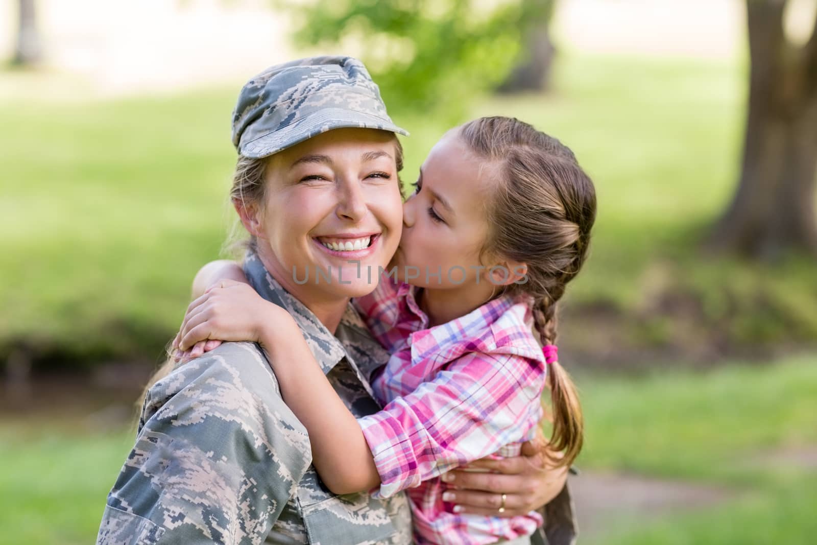 Happy female soldier being kissed by her daughter in park by Wavebreakmedia