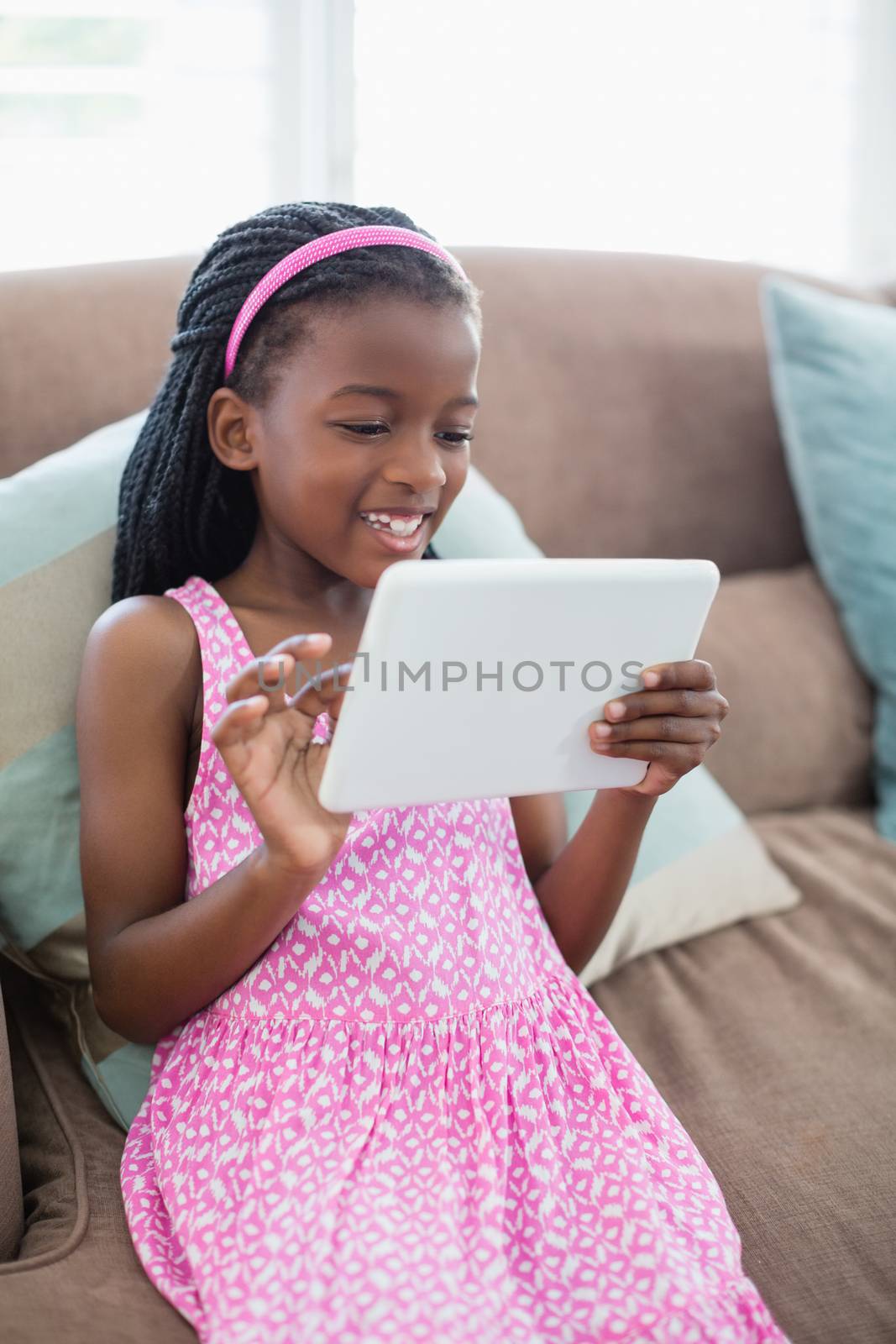 Girl sitting on sofa and using digital tablet in living room at home