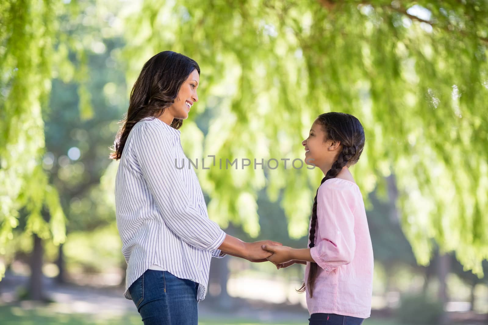 Happy mother holding hands of her daughter in park