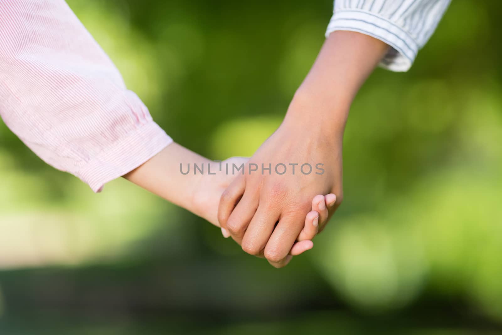 Close-up of mother holding hands of her daughter in park