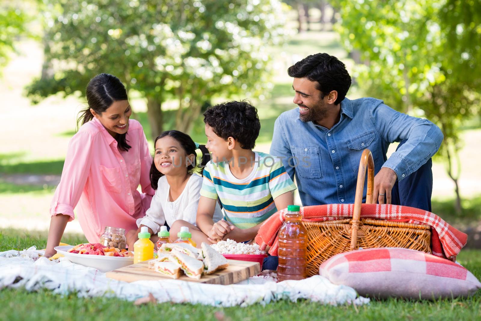 Happy family having breakfast in park on a sunny day