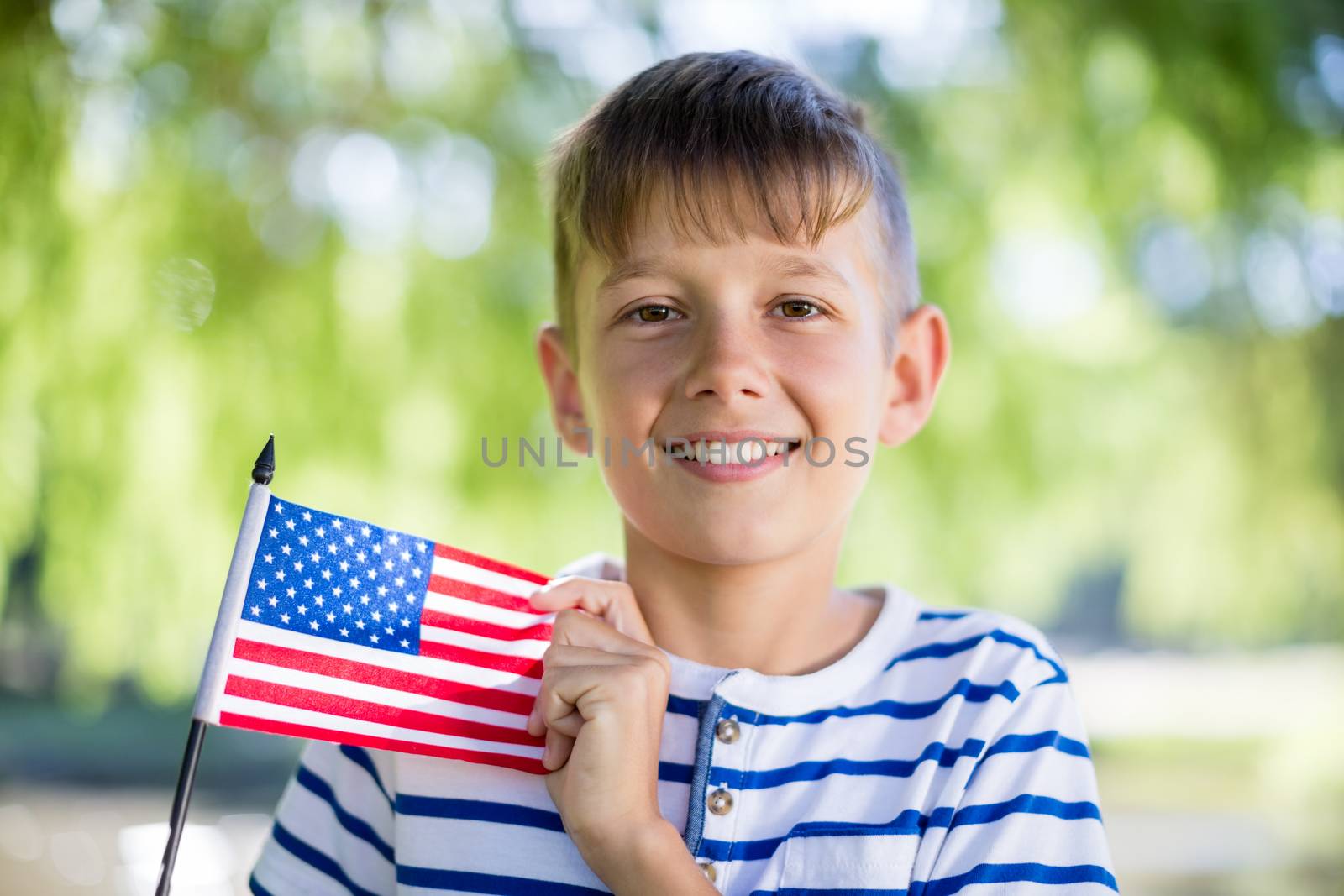 Portrait of boy holding an american flag in park