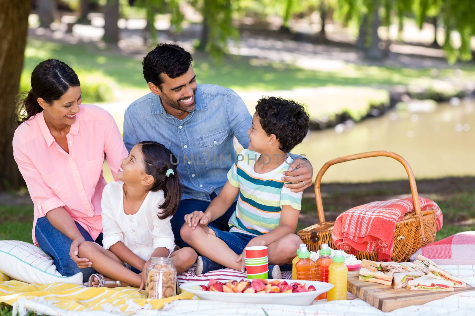 Happy family having breakfast in park on a sunny day