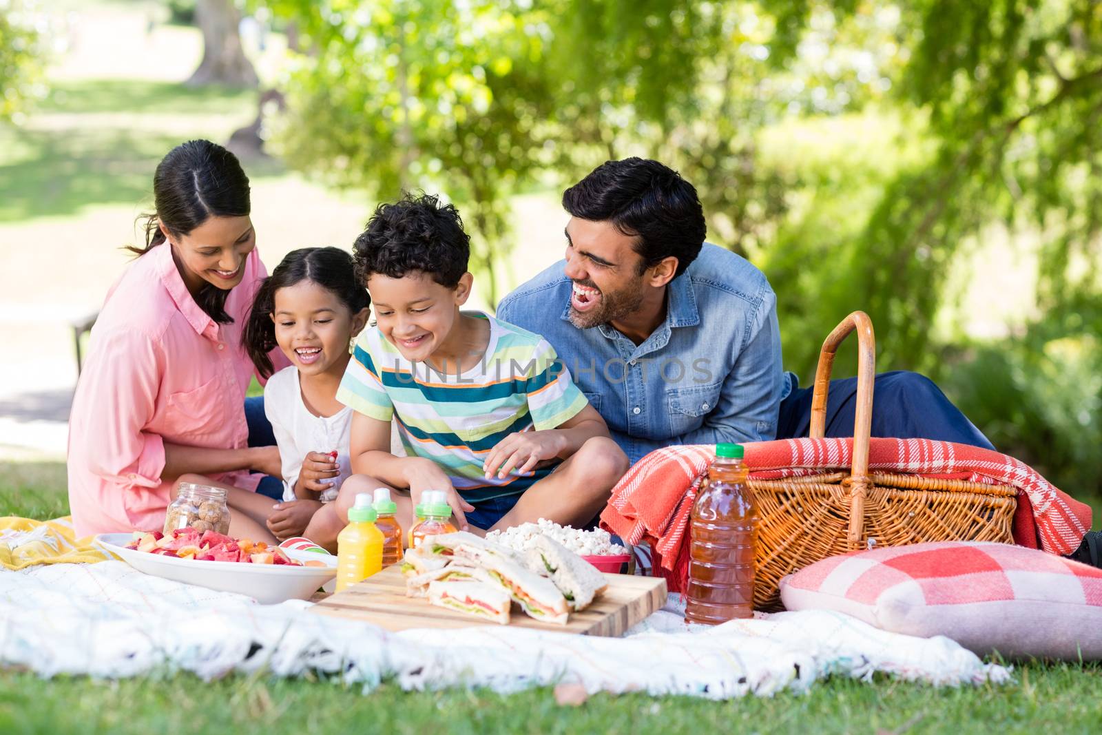 Happy family having breakfast in park on a sunny day