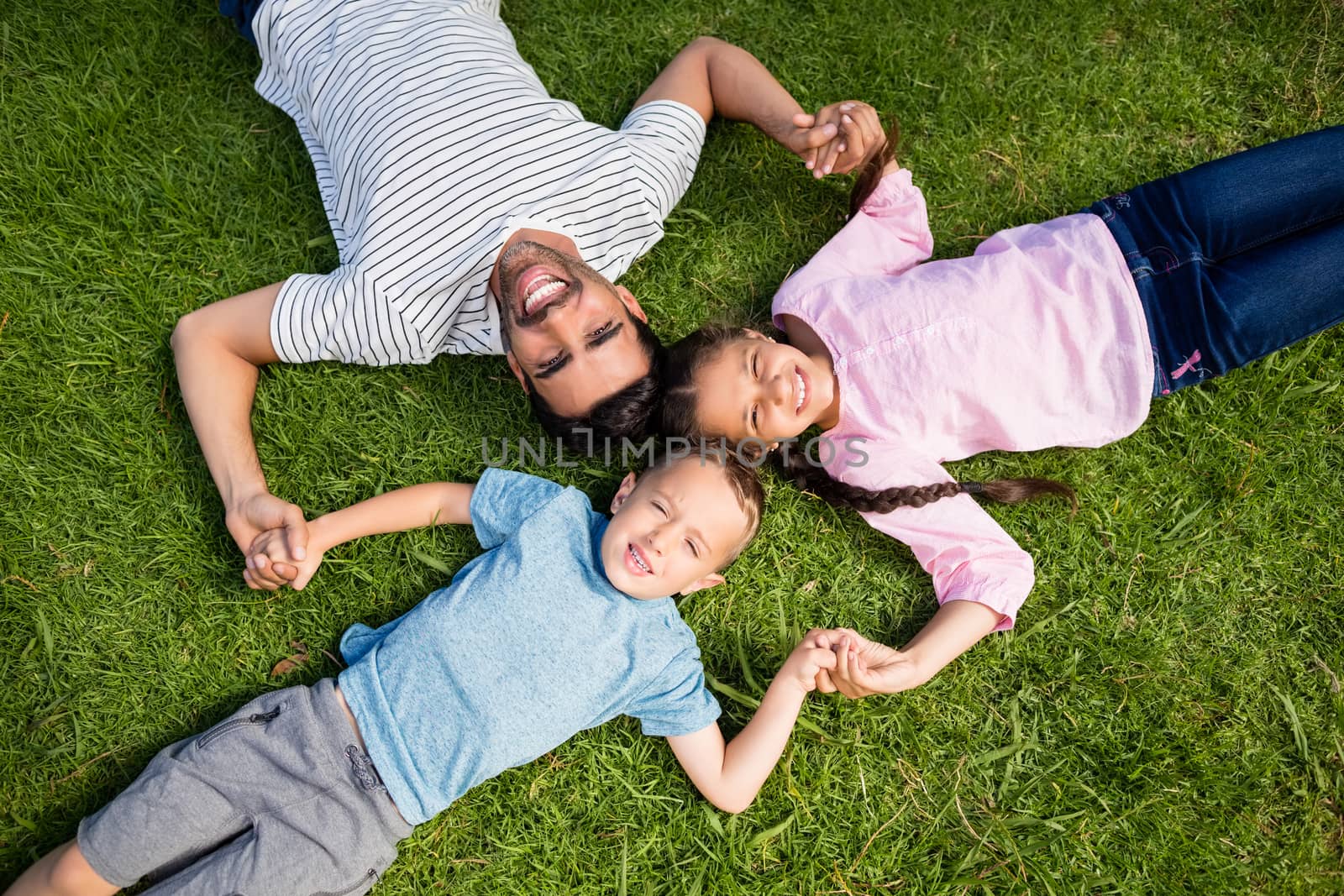 Father having fun with his son and daughter in park on a sunny day