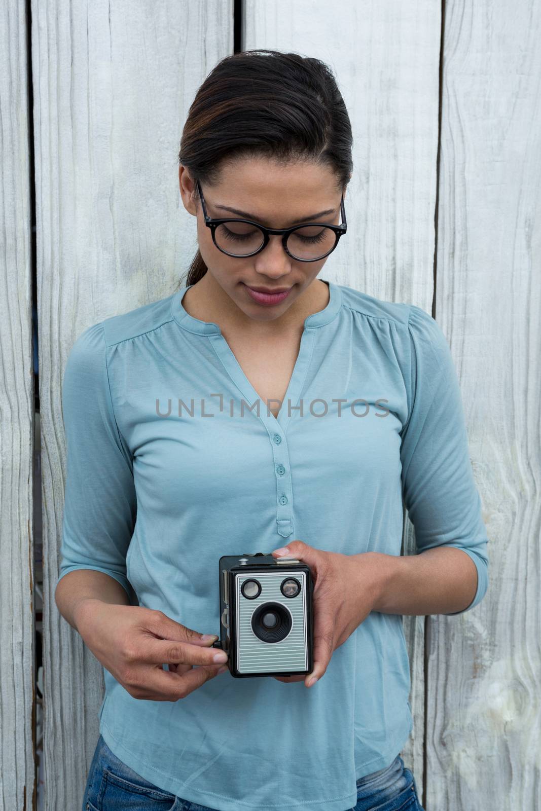 Female photographer with old fashioned camera against wooden background