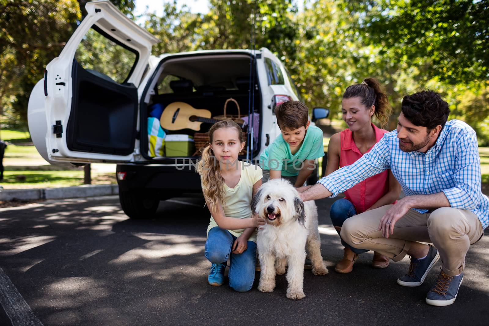 Happy family sitting in the park with their dog