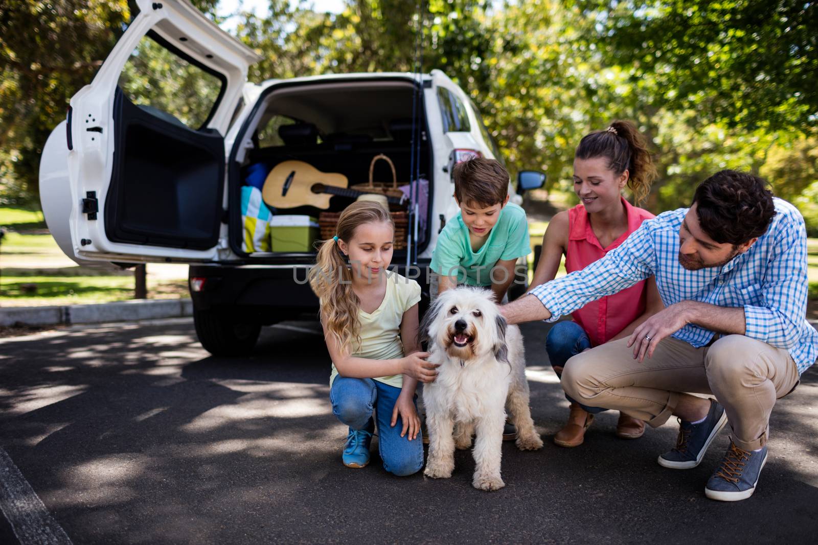 Happy family sitting in the park with their dog