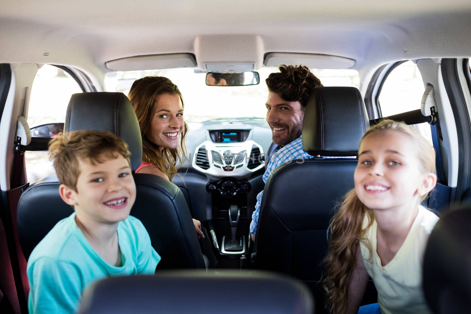 Happy family sitting in car by Wavebreakmedia