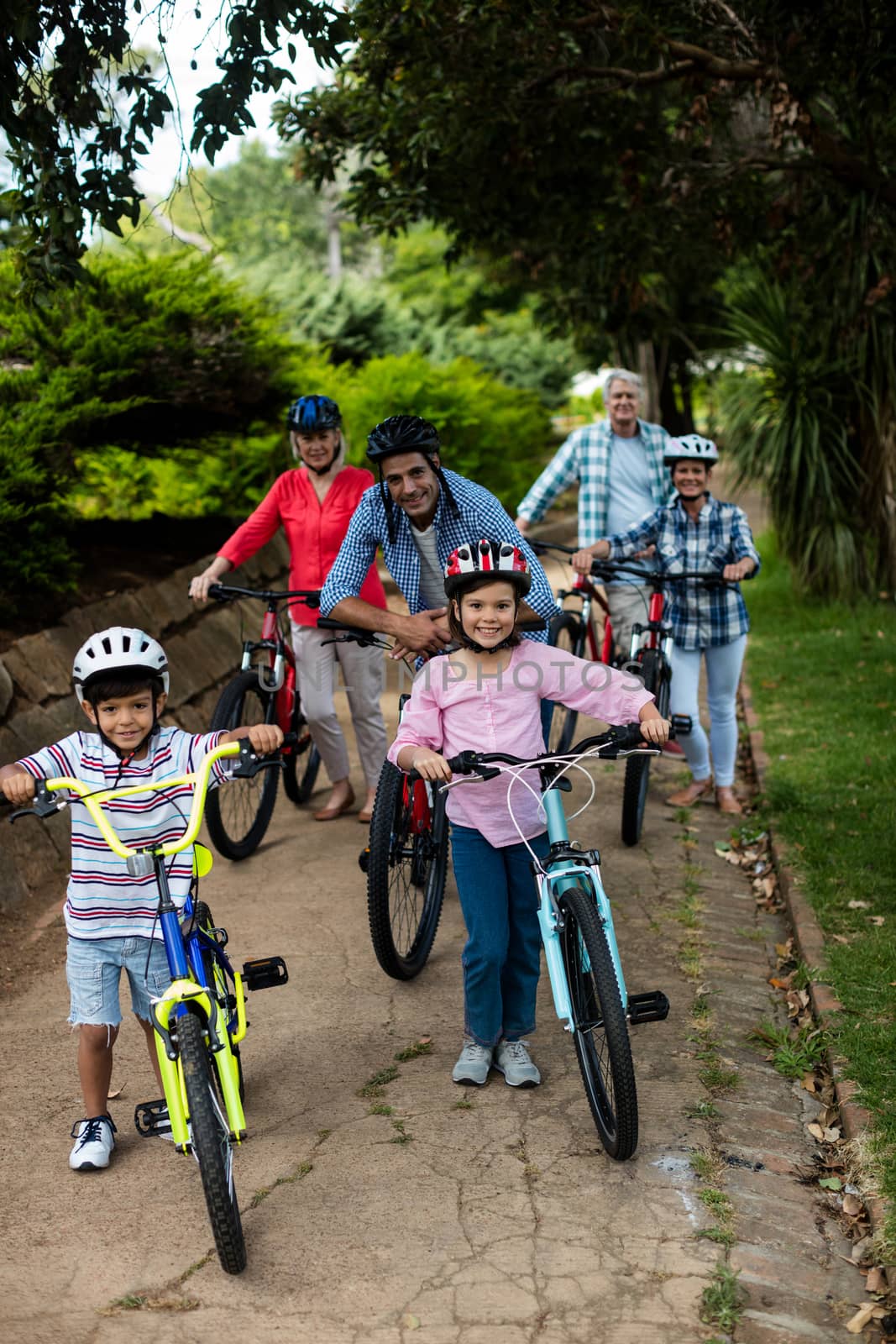 Portrait of multi-generation family standing with bicycle in park by Wavebreakmedia