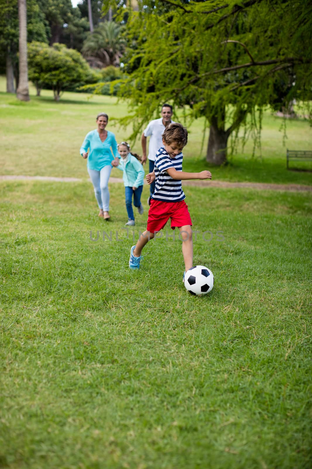 Happy family playing football in park by Wavebreakmedia