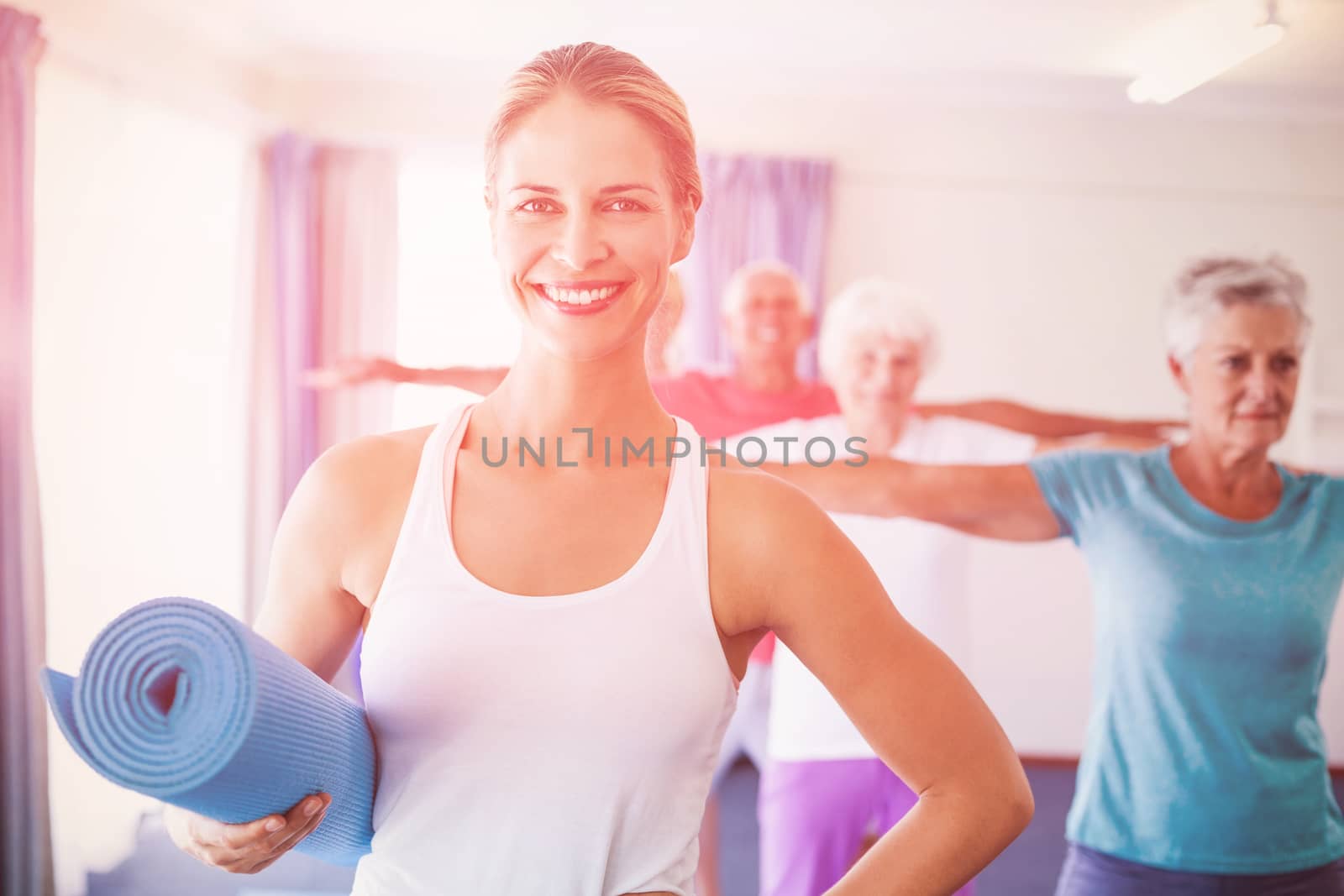 Portrait of Instructor holding yoga mat during sports class
