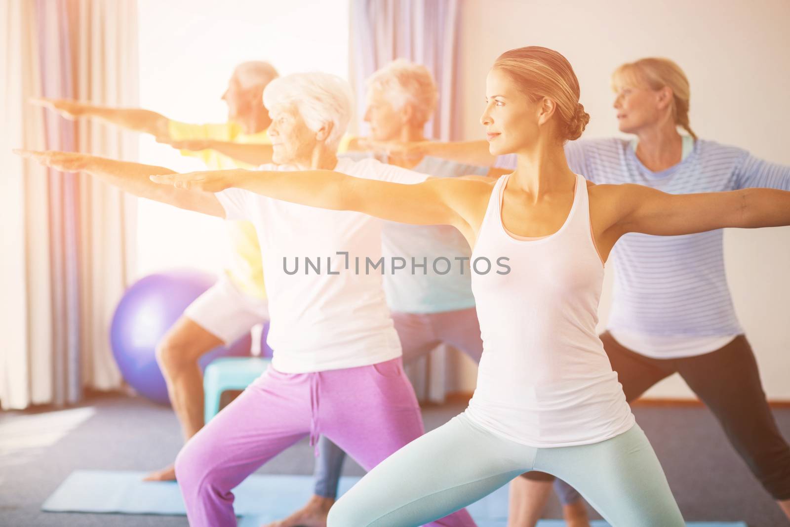 Instructor performing yoga with seniors during sports class